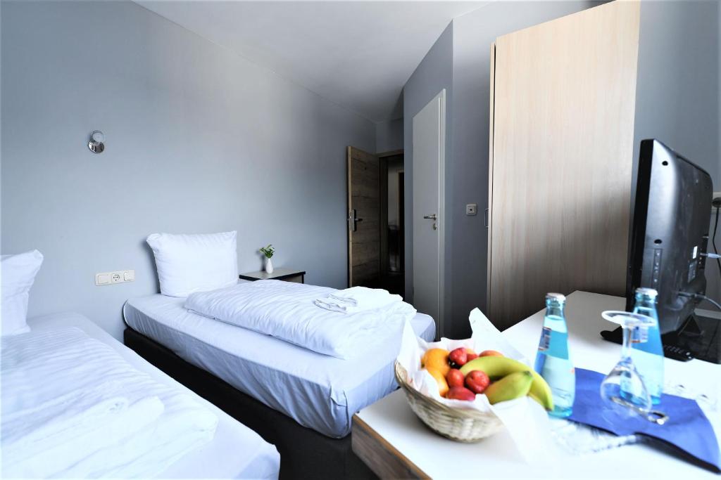 a hotel room with two beds and a bowl of fruit on a table at Hotel Best one in Roßdorf