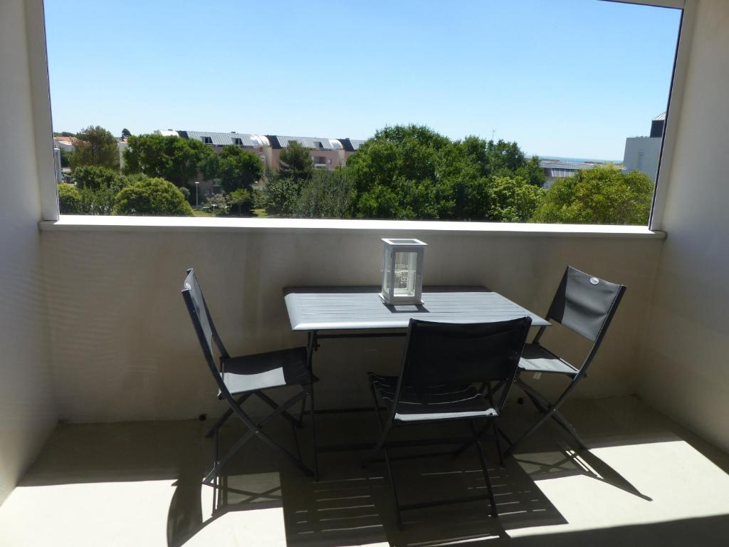d'une table et de chaises sur un balcon avec une fenêtre. dans l'établissement Plage des Minimes Résidence Clarines, à La Rochelle