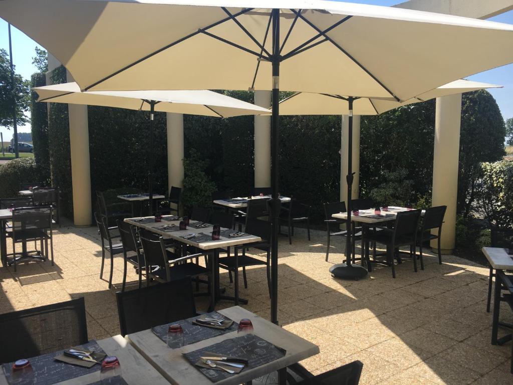 a restaurant with tables and umbrellas on a patio at Hôtel Relais d'Étretat in Bolbec