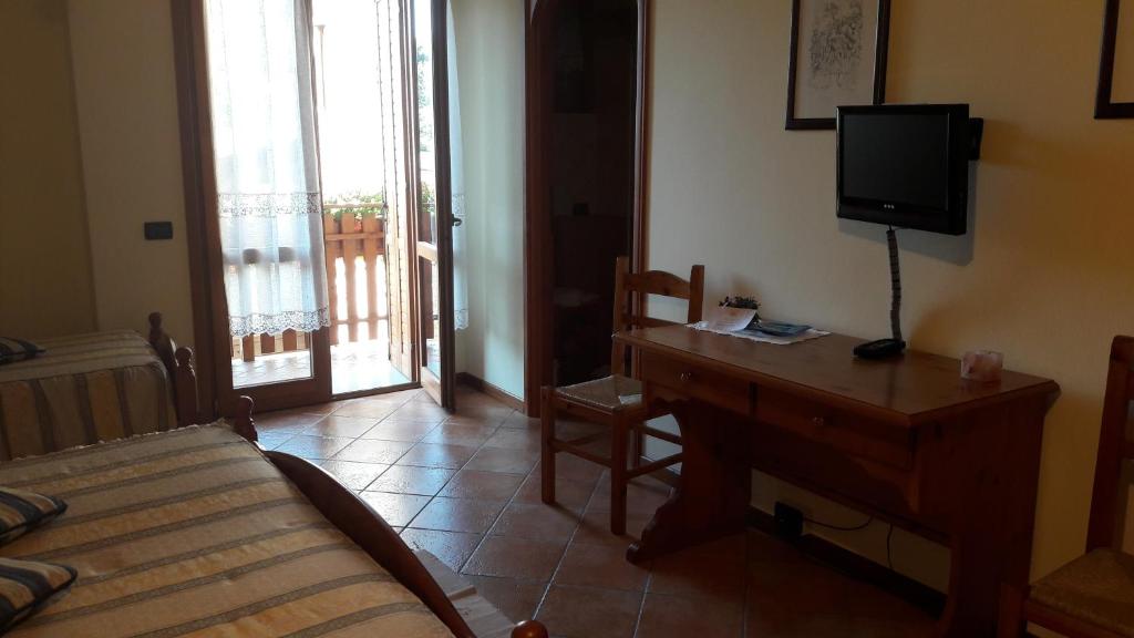 una camera con letto e scrivania con TV di I Camuni a Capo di Ponte