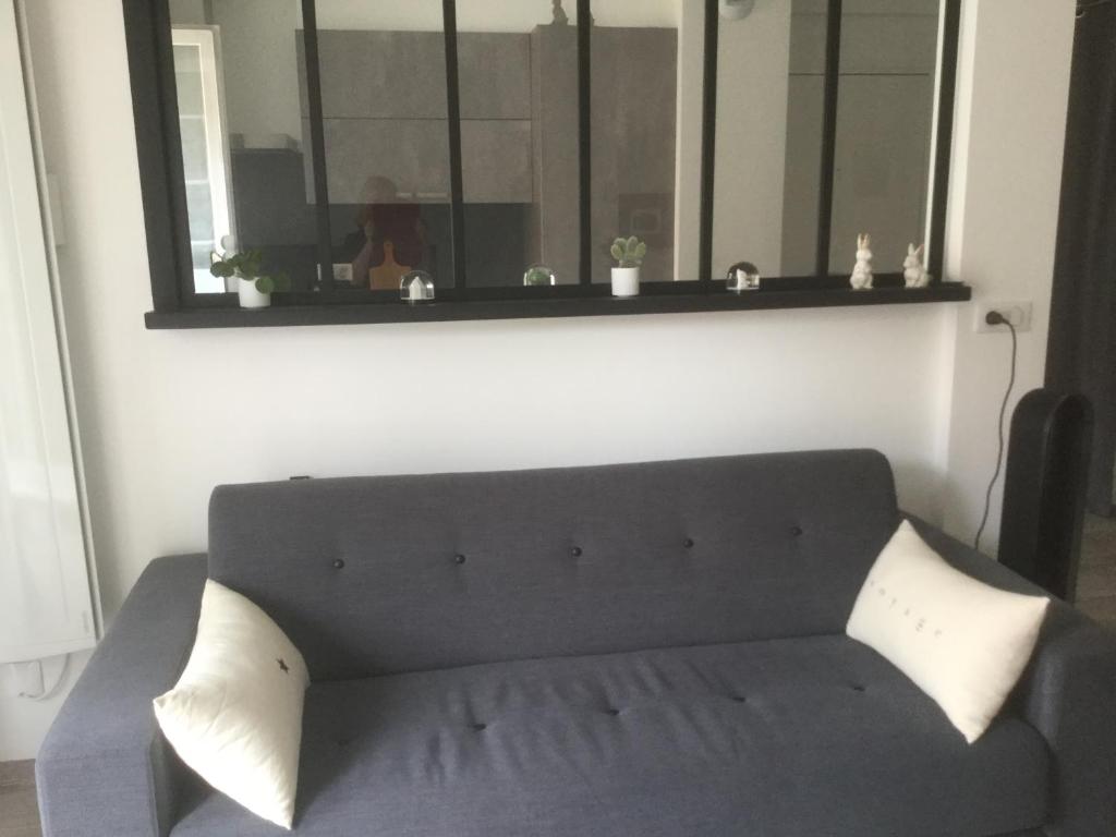 - un canapé noir dans le salon avec un miroir dans l'établissement Les grenettes2, à Metz