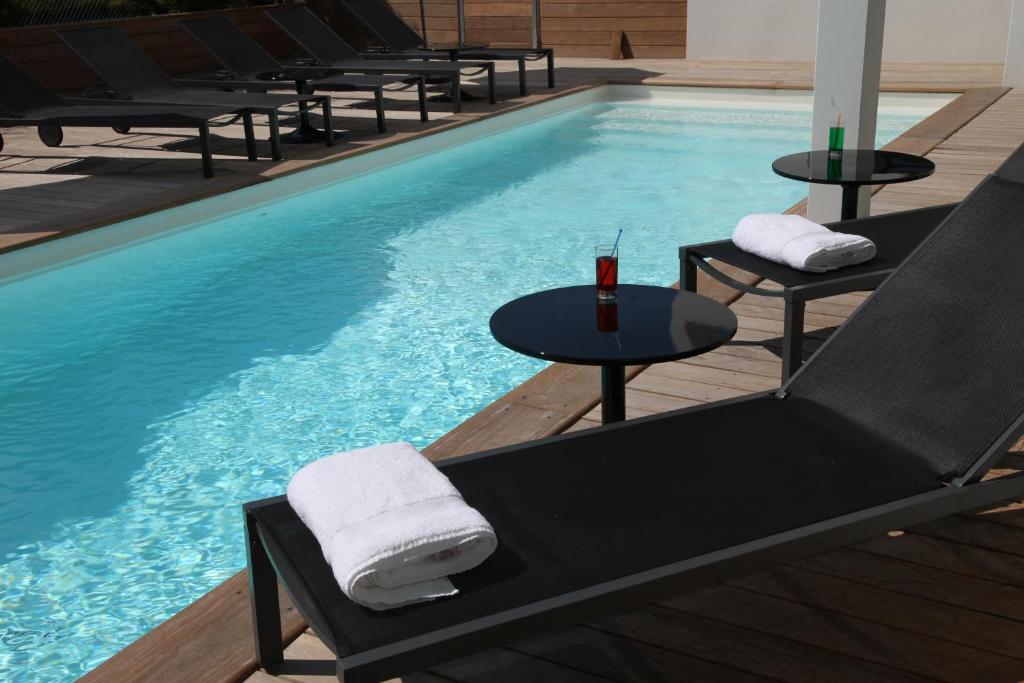 a swimming pool with chairs and a table in front of it at Hotel 202 in Hossegor