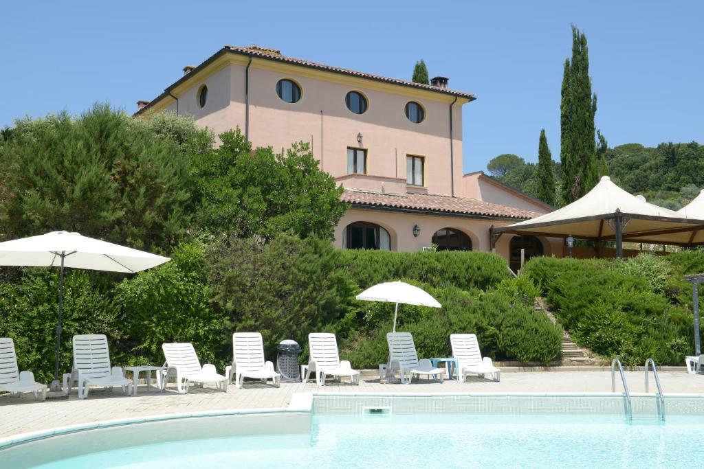 a pool with chairs and umbrellas in front of a building at Residence Il Granaio in Riparbella