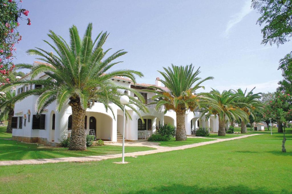 a house with palm trees in front of it at APARTAMENTOS SON BOU Z5 in Son Bou