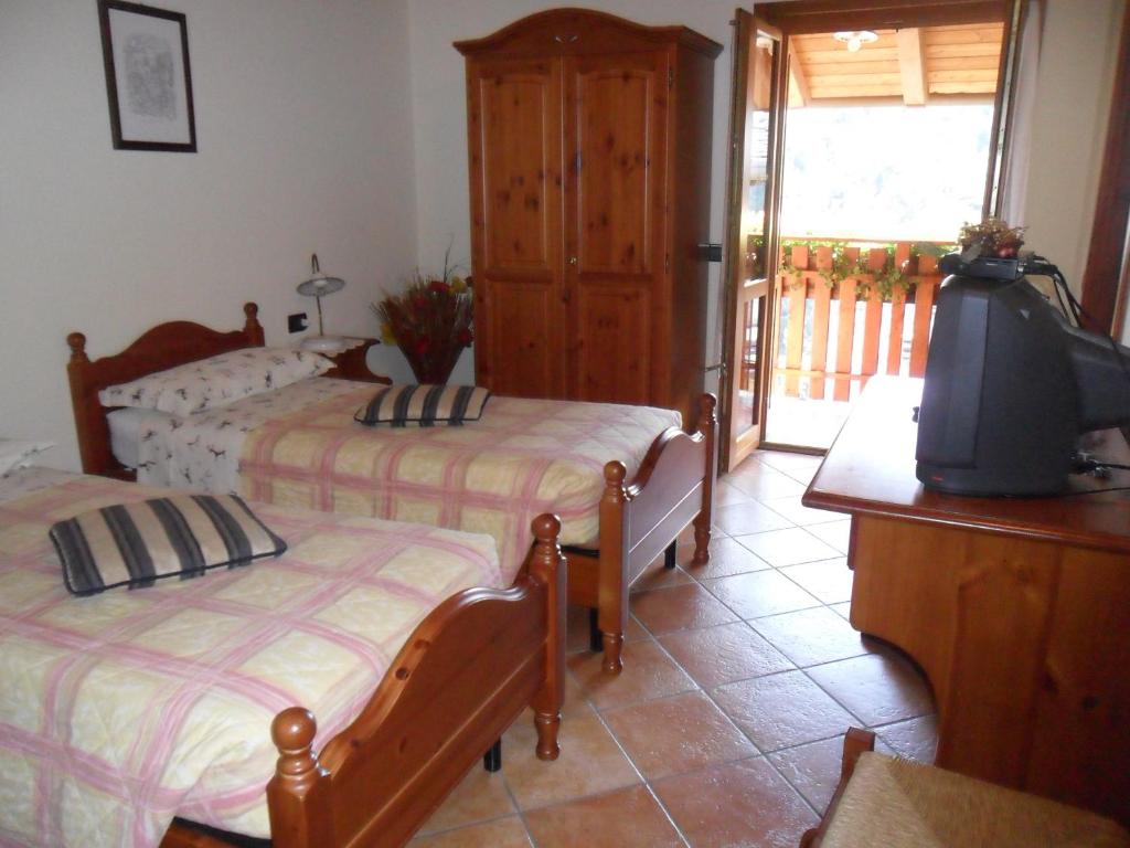 a bedroom with two beds and a television and a balcony at I Camuni in Capo di Ponte