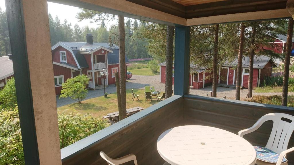 Kolbacken stugby & Camping في Åsarne: شرفة مع طاولة وكراسي وإطلالة على منزل
