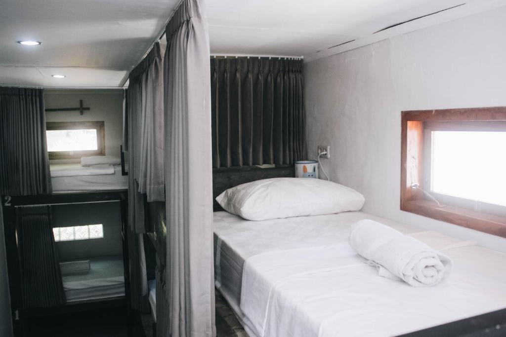 um pequeno quarto com 2 camas e uma janela em Mellow Hostel em Kuta Lombok