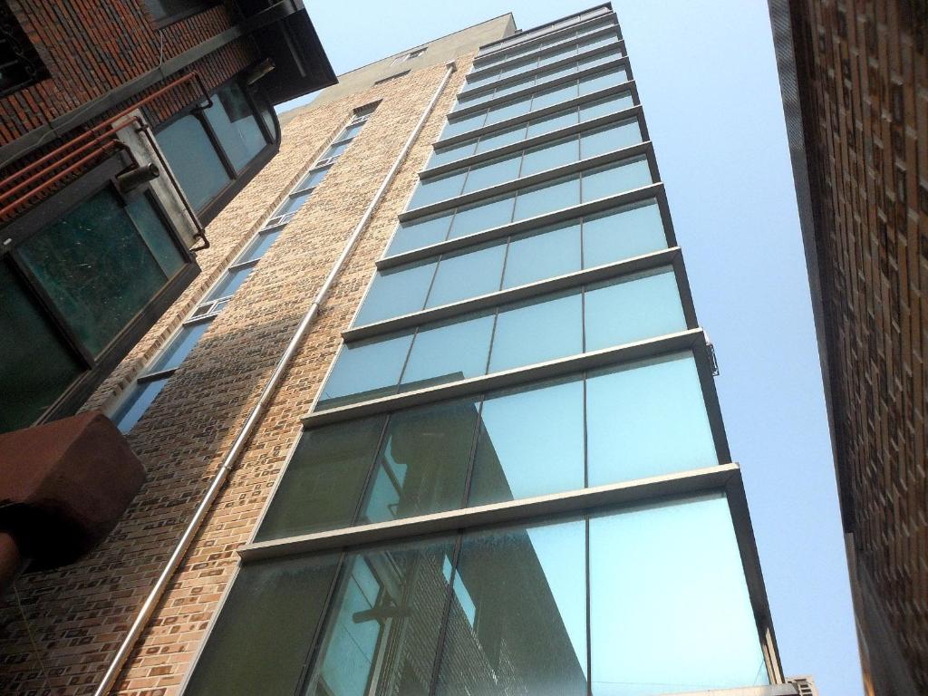 a tall building with glass windows on the side of it at Gangnam Suncity Guesthouse in Seoul