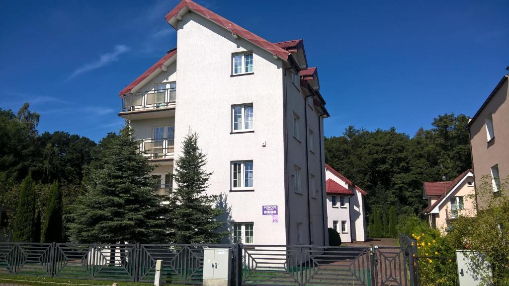 a white building with a red roof at Pokoje Gościnne - Leśna 8 in Ustronie Morskie