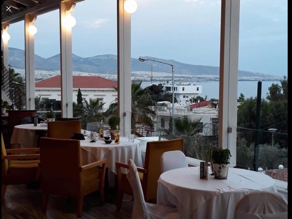 a restaurant with tables and chairs and a large window at Cavo D' Oro in Piraeus