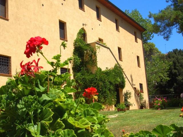 duży budynek z czerwonymi kwiatami przed nim w obiekcie Agriturismo Lupo Vecchio w mieście Grosseto