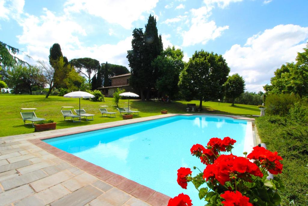 a swimming pool with red flowers in a yard at Villa Cecilia in Castiglion Fiorentino