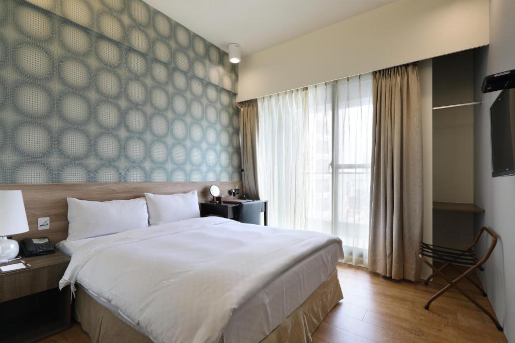 a bedroom with a large bed and a large window at KUN Hotel in Taichung