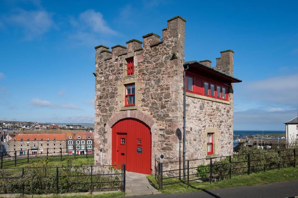 un edificio con una puerta roja a un lado. en Nisbet's Tower, en Eyemouth
