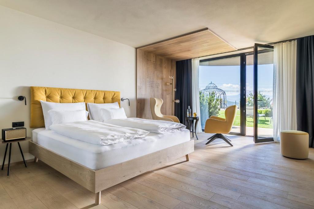 una camera con un grande letto e una grande finestra di Gloriette Guesthouse Hotel & Restaurant a Soprabolzano