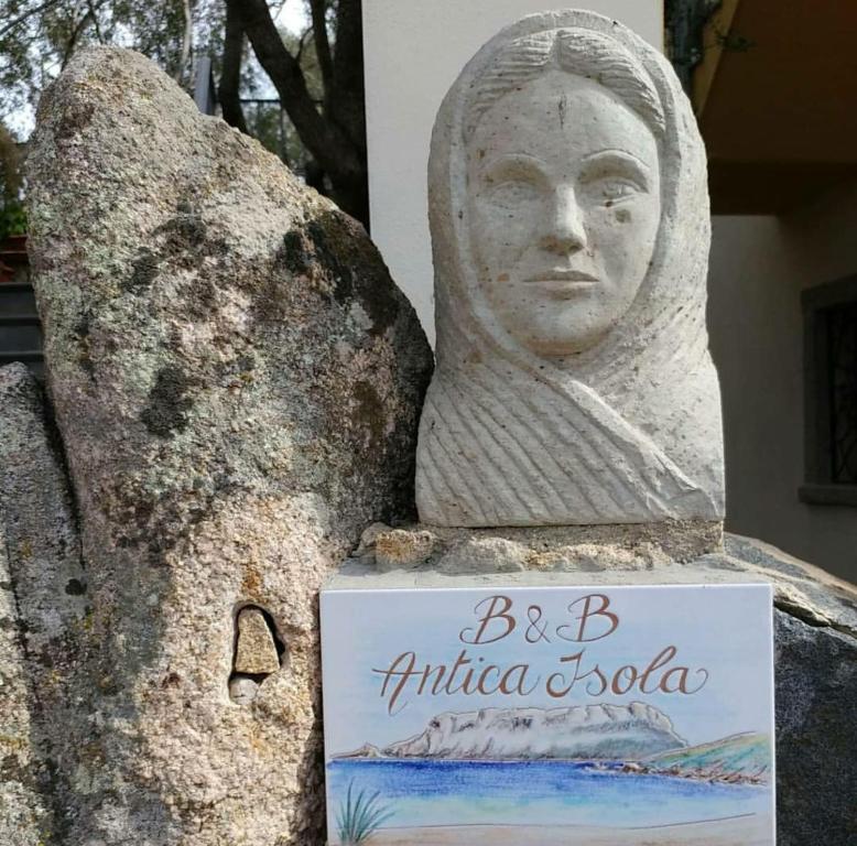 una estatua de una mujer parada junto a una roca en Antica Isola, en Olbia