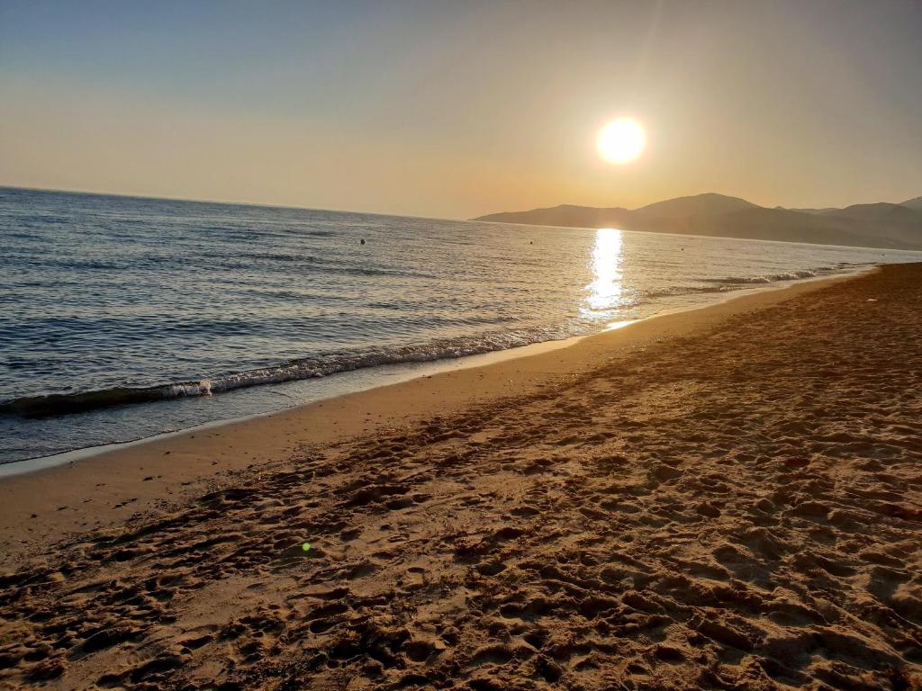 a beach with the sun rising over the ocean at Magicomar Hotel in Ascea