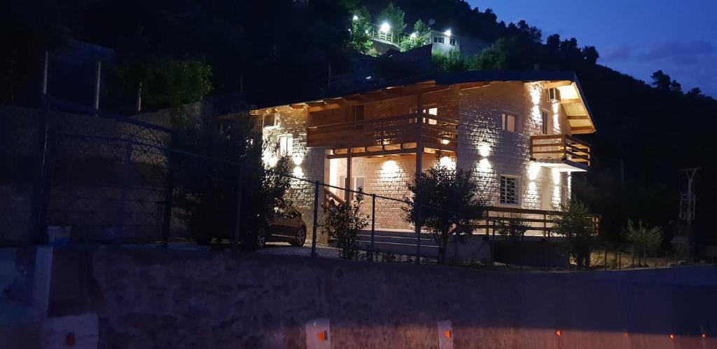 uma casa numa colina à noite com luzes em Hotel Grandpa's House em Shkodër
