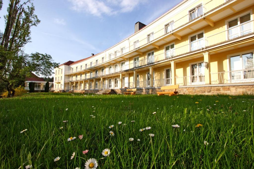 un gran edificio con un campo de hierba y flores en Akzent Hotel Am Burgholz, en Tabarz