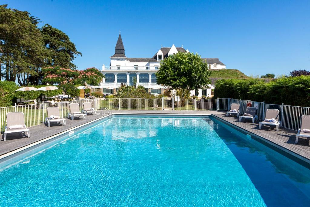 une piscine avec des chaises et une maison en arrière-plan dans l'établissement Hotel Restaurant Spa du Tumulus Carnac, à Carnac