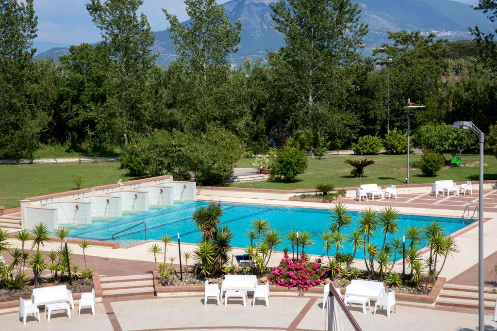 einen großen Pool mit weißen Stühlen und Bäumen in der Unterkunft Grand Hotel Paestum in Paestum