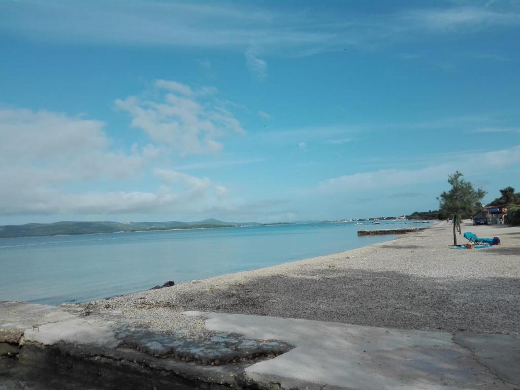 eine Person, die am Strand neben dem Wasser sitzt in der Unterkunft Family apartment near beach in Biograd na Moru