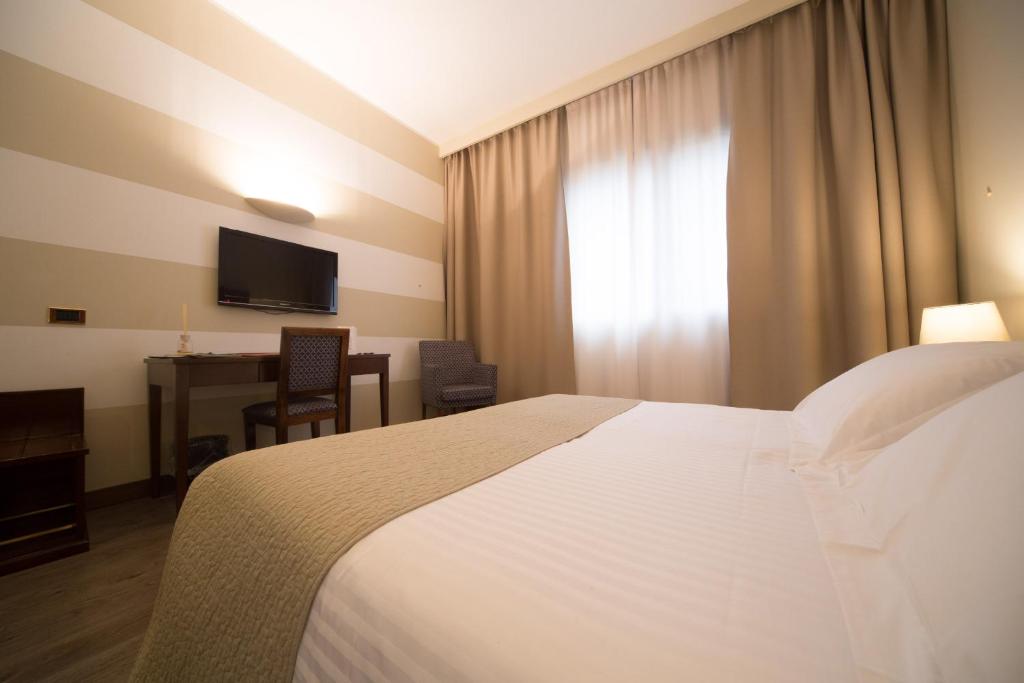 a hotel room with a bed and a desk and a television at Hotel Motel Ascot in Lissone
