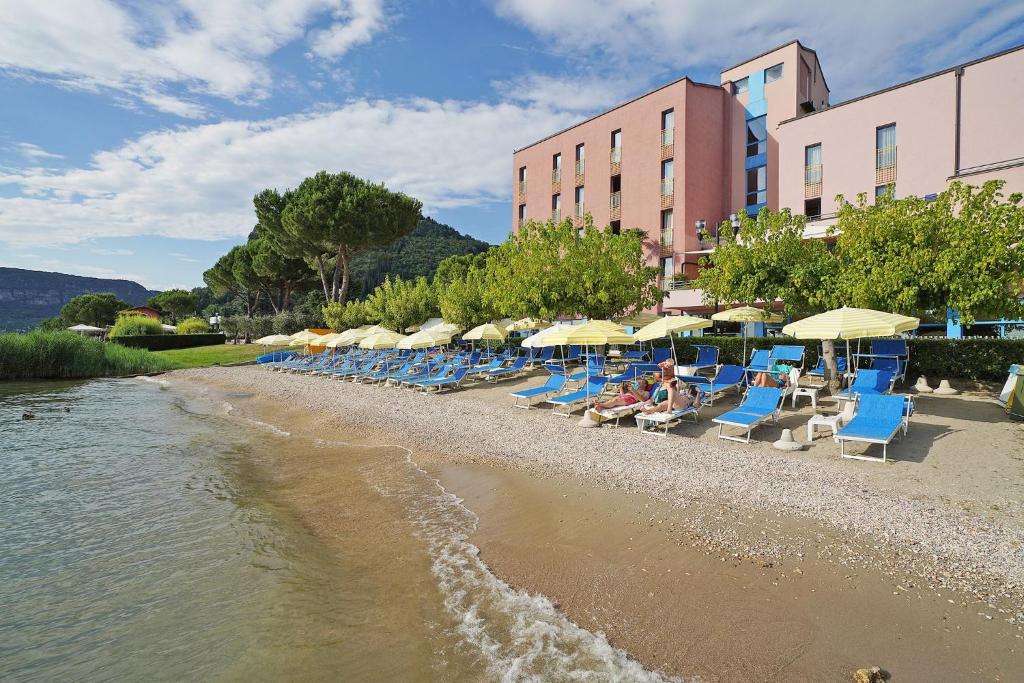 a row of tables with umbrellas on the beach at Hotel Sportsman in Bardolino