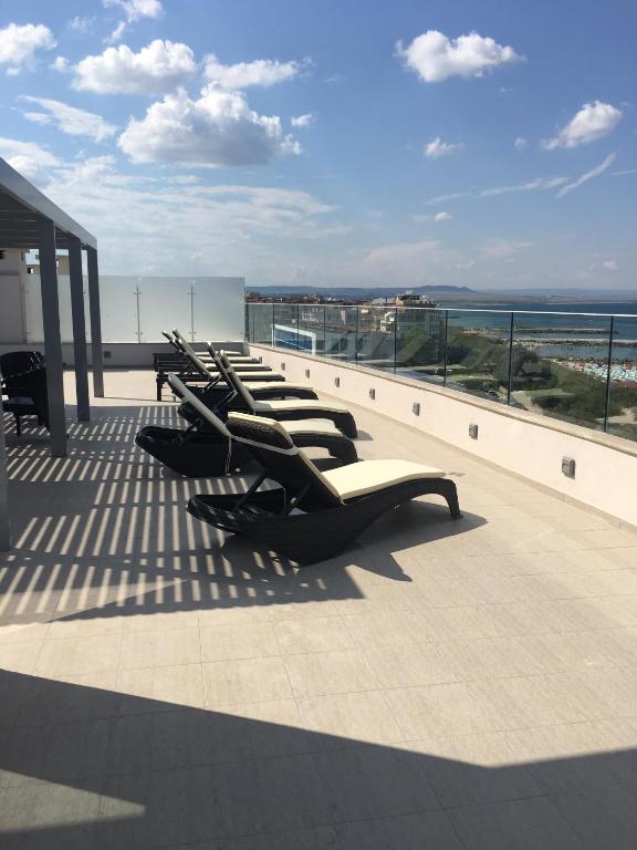 a row of lounge chairs on the roof of a building at Golden Sea View Penthouse in Pomorie