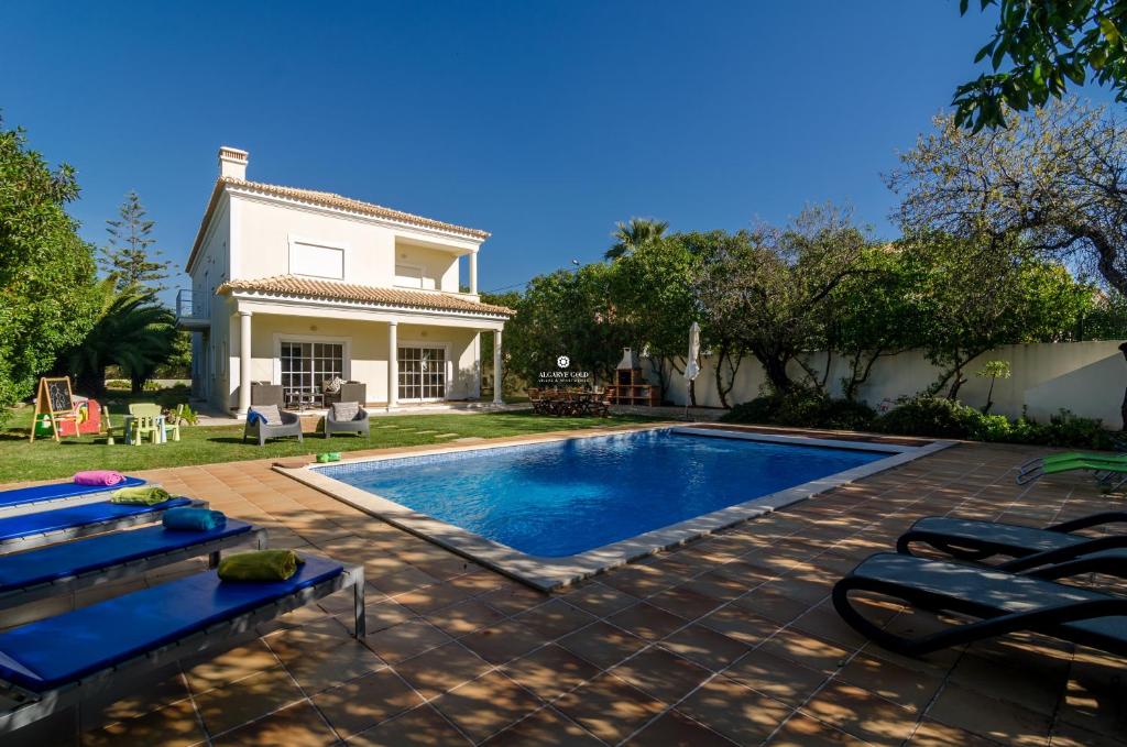 a swimming pool in front of a house at Villa Amendoeiras in Quartos