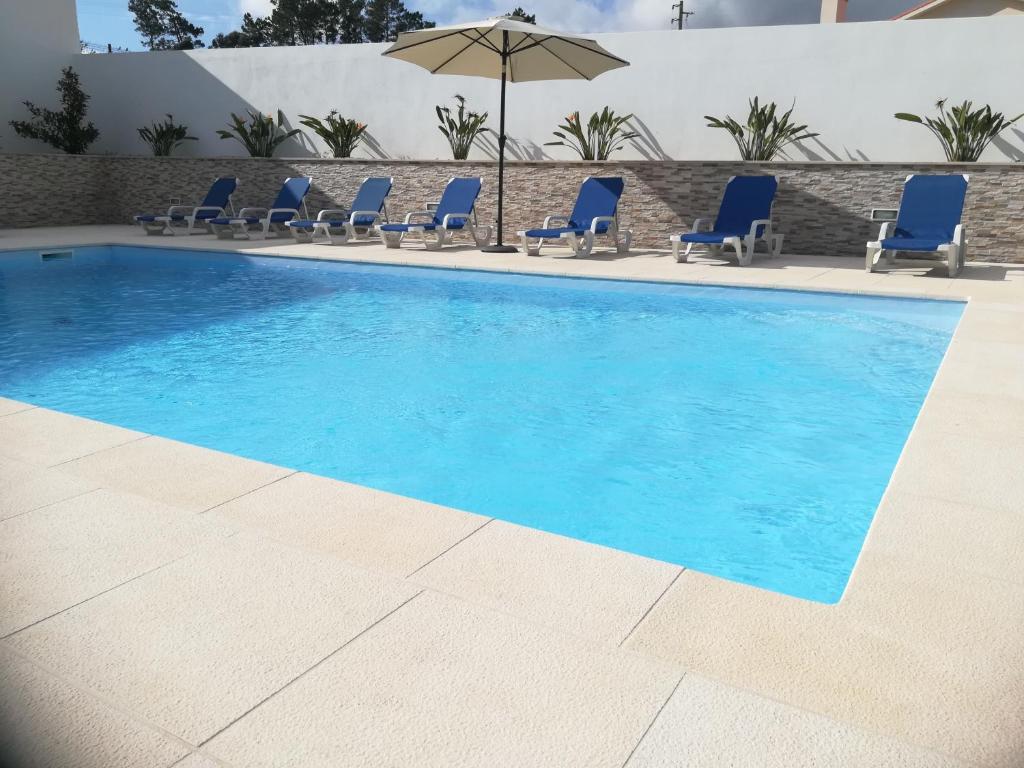 - une piscine avec des chaises et un parasol dans l'établissement Alojamentos Campo & Mar - Vivenda Golden House, à Bica