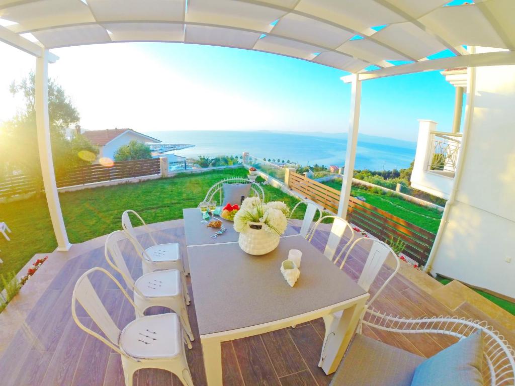 a table and chairs on a porch with a view of the ocean at #Luxlikehome - Villa Vista al Mar in Paliouri
