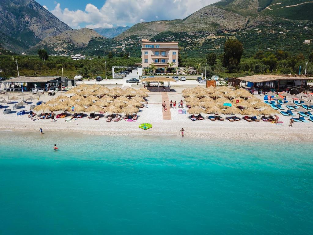 una playa con sillas y sombrillas y gente en la playa en Sole Luna Hotel, en Borsh