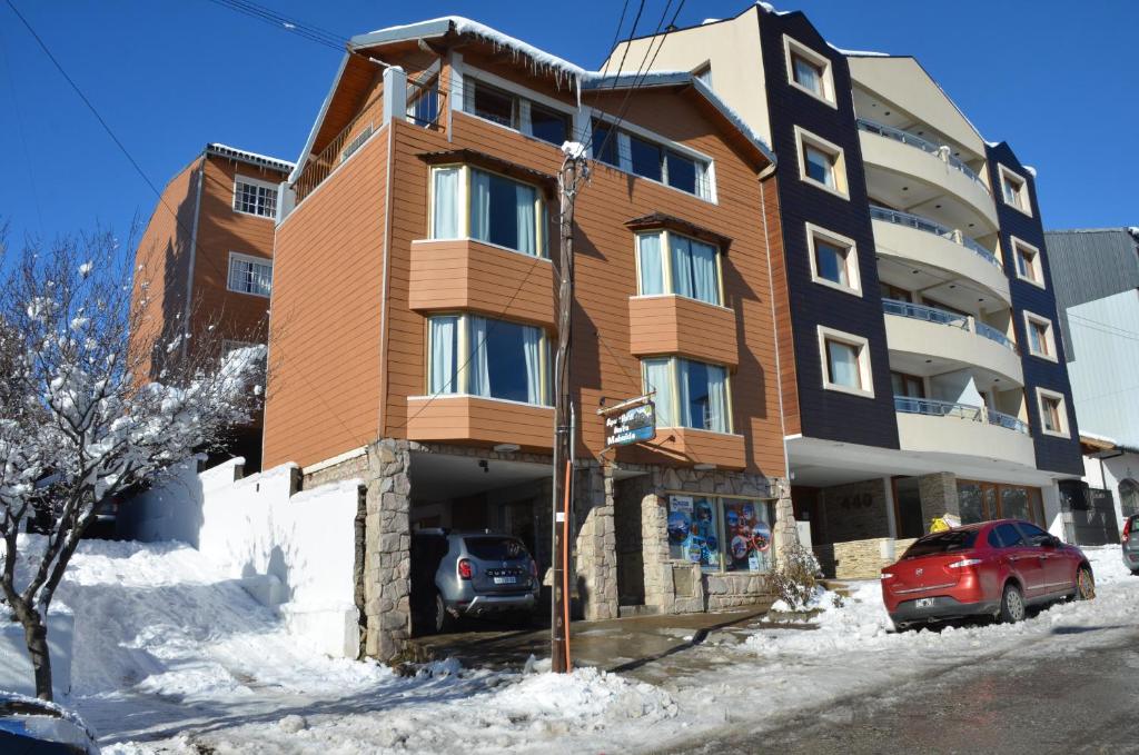 un edificio con un coche rojo estacionado frente a él en Antu Mahuida Apartments en San Carlos de Bariloche