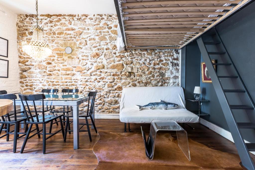 Cosy 40m² near MONTMARTRE في باريس: غرفة طعام مع طاولة وكراسي وجدار من الطوب