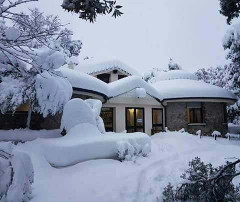 una casa cubierta de nieve frente a una casa en Hotel Bosco Selene en Lanusei