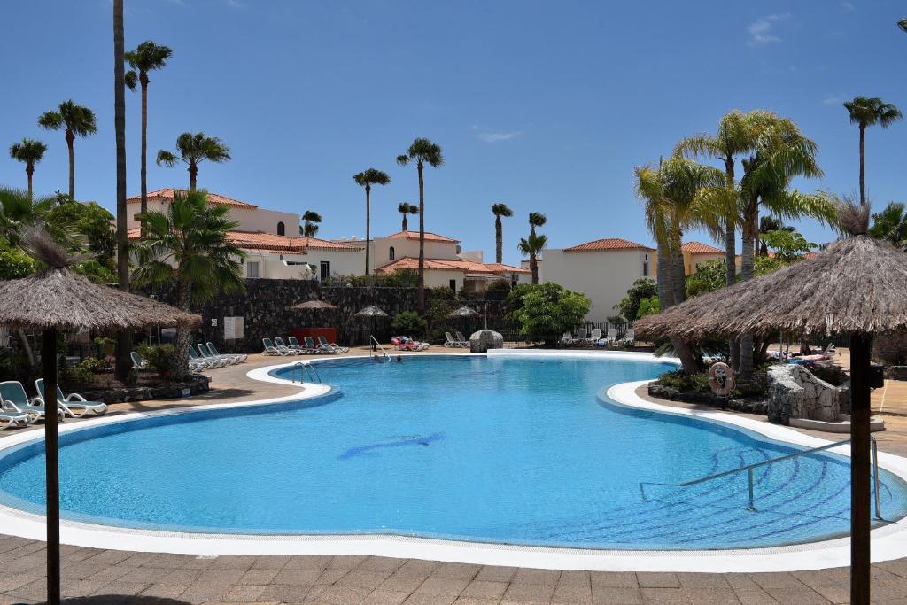 a swimming pool at a resort with palm trees at Las Adelfas 2 in San Miguel de Abona