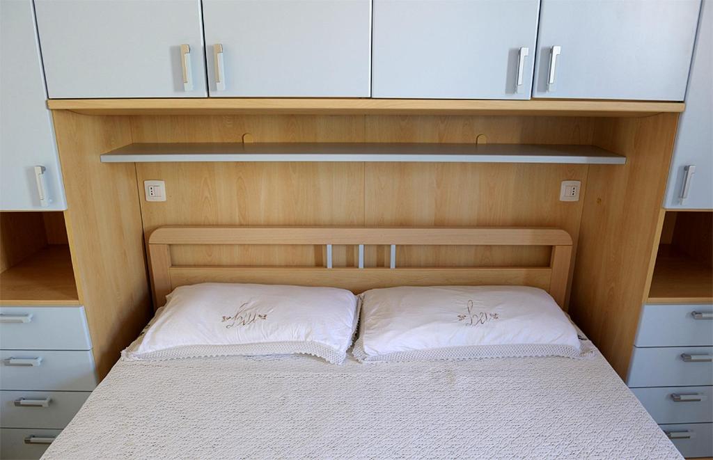 ein kleines Schlafzimmer mit einem Bett mit weißen Kissen in der Unterkunft L'arcobaleno in Valledoria