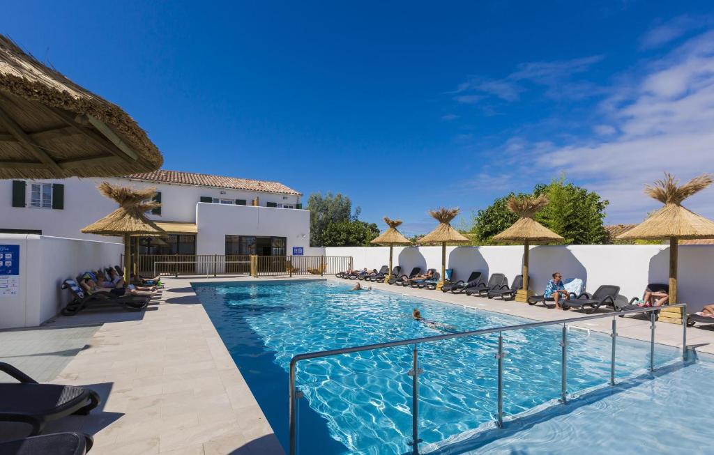 uma piscina num resort com cadeiras e guarda-sóis em Résidence Prestige Odalys Rêve d'île em Rivedoux-Plage