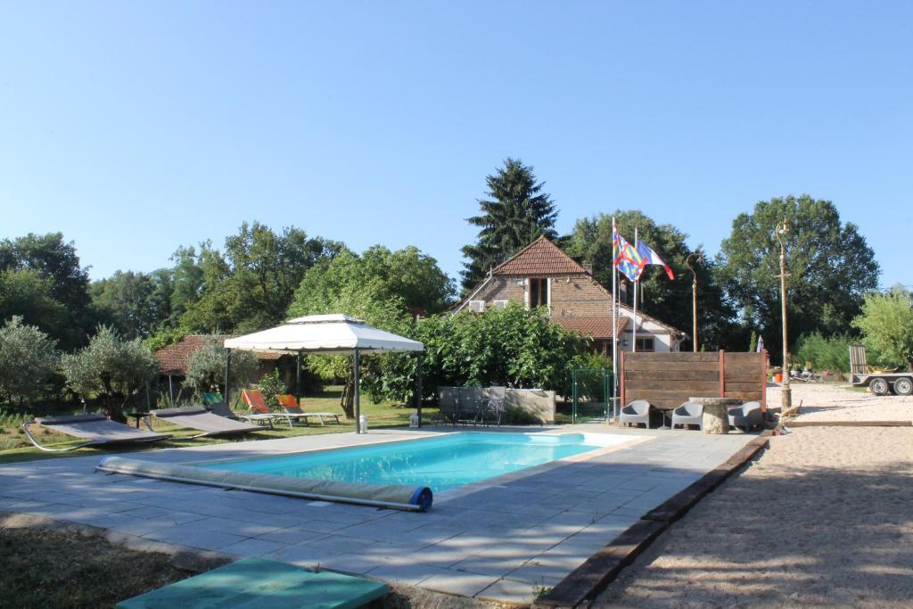 una piscina con sombrilla y una casa en La Petite Ferme du Marais en Saint-Germain-du-Bois