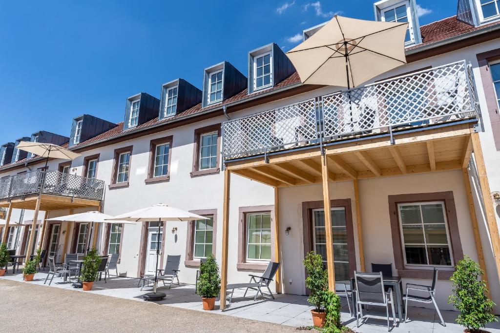 a building with a balcony with chairs and umbrellas at Parkside Boutique Appartements in Herbolzheim