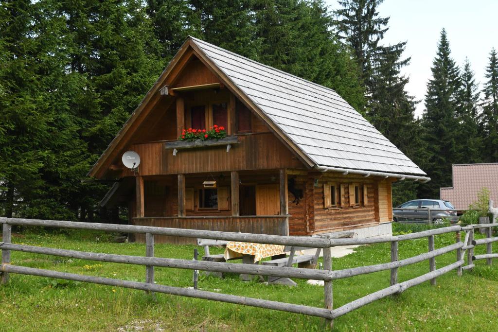 ein kleines Holzhaus mit einem Fenster und einem Zaun in der Unterkunft POČITNIŠKA HIŠA JURČEK POKLJUKA in Goreljek