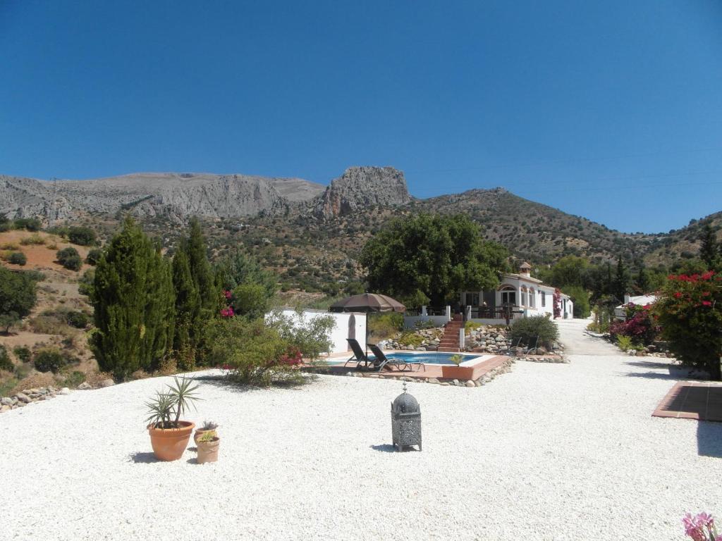 un gran patio con una casa y montañas al fondo en Casa el Chorro en El Chorro