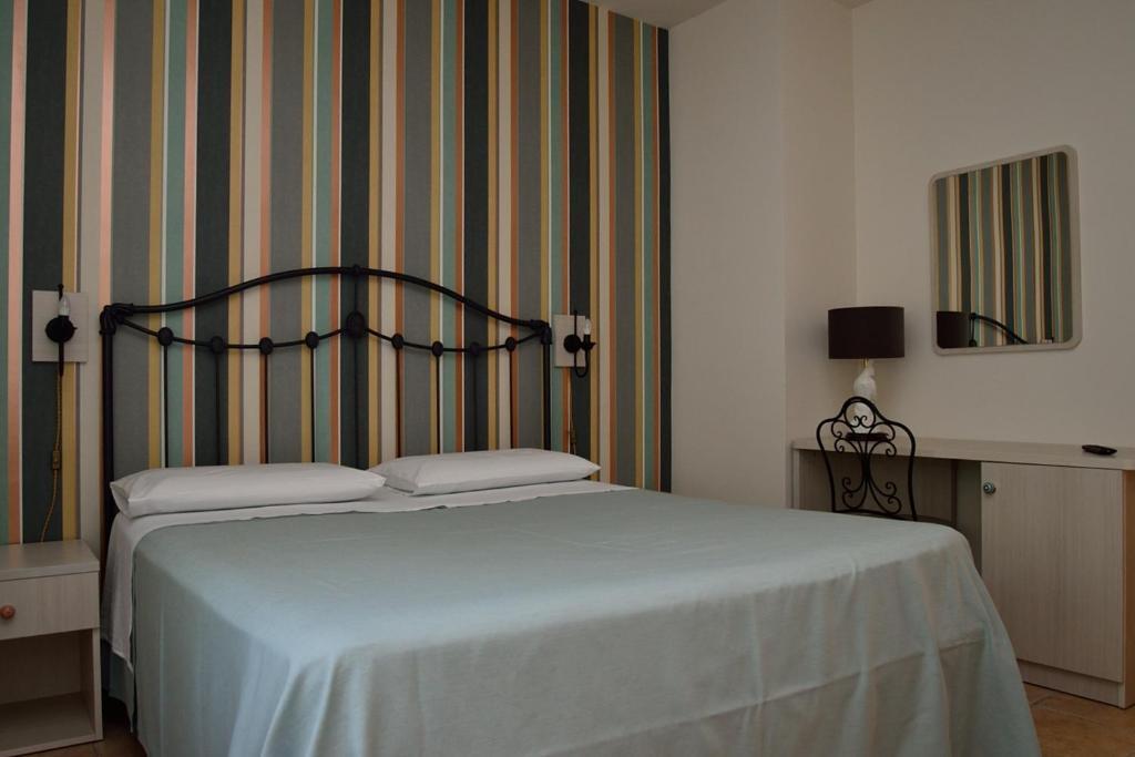 sypialnia z łóżkiem i ścianą w paski w obiekcie Alloggio nonna Cornelia w mieście Citta' Sant'Angelo