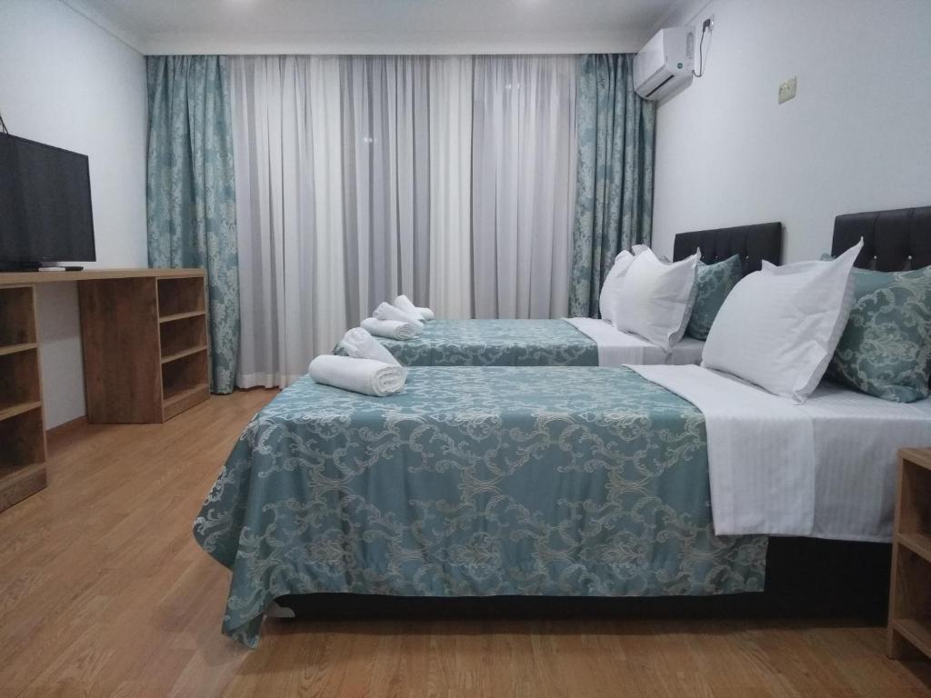 a hotel room with two beds and a flat screen tv at Dzveli Batumi in Batumi
