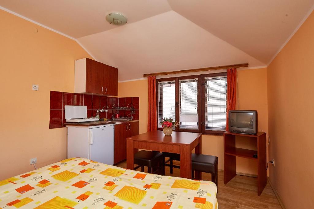 a bedroom with a bed and a table and a kitchen at Apartmani Malica in Soko Banja