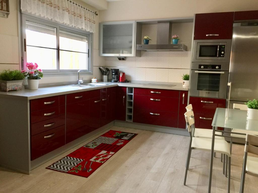 uma cozinha com armários vermelhos e uma mesa com cadeiras em Pozo Izquierdo Global Paradise em Pozo Izquierdo