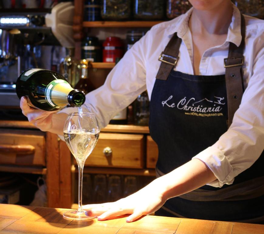 a woman pouring wine into a wine glass at Logis Hôtel et Spa Le Christiania in La Salle-les-Alpes