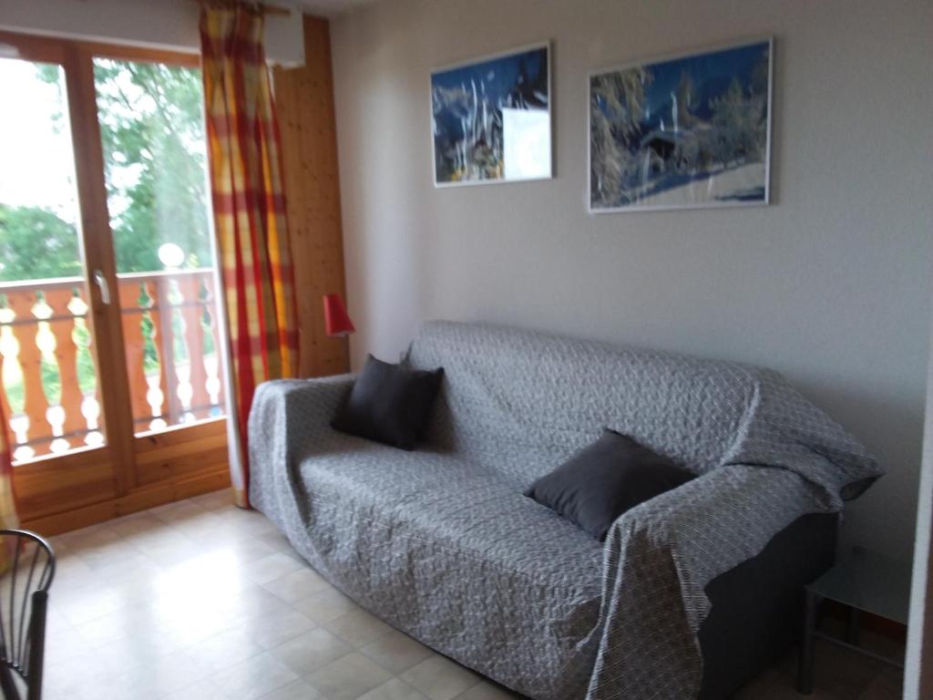 a living room with a couch and a balcony at STUDIO entre ciel et Lac in Thollon