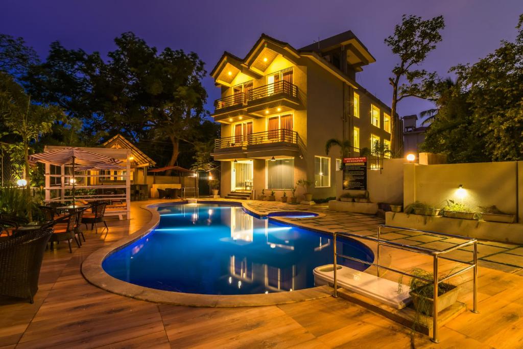 a pool in front of a house at night at Ramatan Resort in Vagator